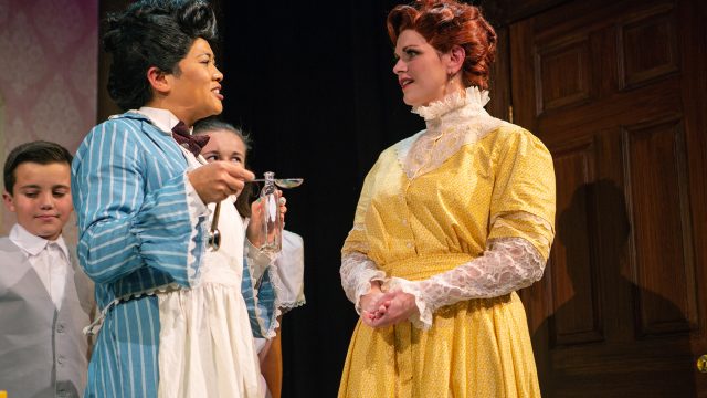 Mary Poppins (El Beh) offers Winifred Banks (Abby Haug*), Michael Banks (Billy Hutton), and Jane Banks (Grace Hutton) a 'spoonful of sugar'.