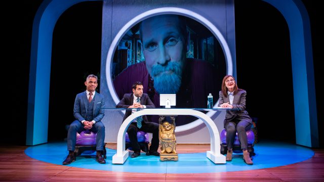 Fred (Ryan Morales), Raj (Bobak Cyrus Bakhtiari*), and Joan (Susi Damilano*) are on a conference call with Jojomon founder John Dale (Craig Marker*).