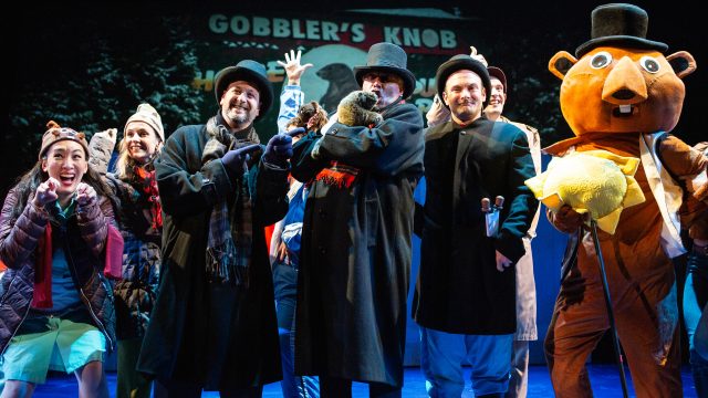 The residents of Punxsutawney, PA, are excited about Groundhog Day. Featuring (l-r): Kathryn Hannah*, Larissa Kelloway, David Schiller, Michael Gene Sullivan*, Michael Motroni, Dean Linnard*, and Montel Anthony Nord (in groundhog costume).