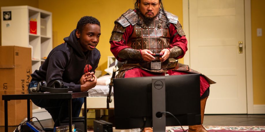 Jayden (Leon Jones) watches as Temujin (Brian Rivera*) begins to play a video game in 'The Great Khan' by Michael Gene Sullivan at San Francisco Playhouse.