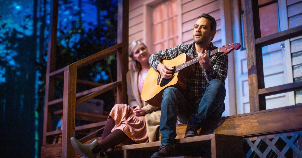 Emily (Wera von Wulfen) watches Justin (Johnny Moreno*) play guitar on the back porch in 'Heroes of the Fourth Turning' at San Francisco Playhouse.