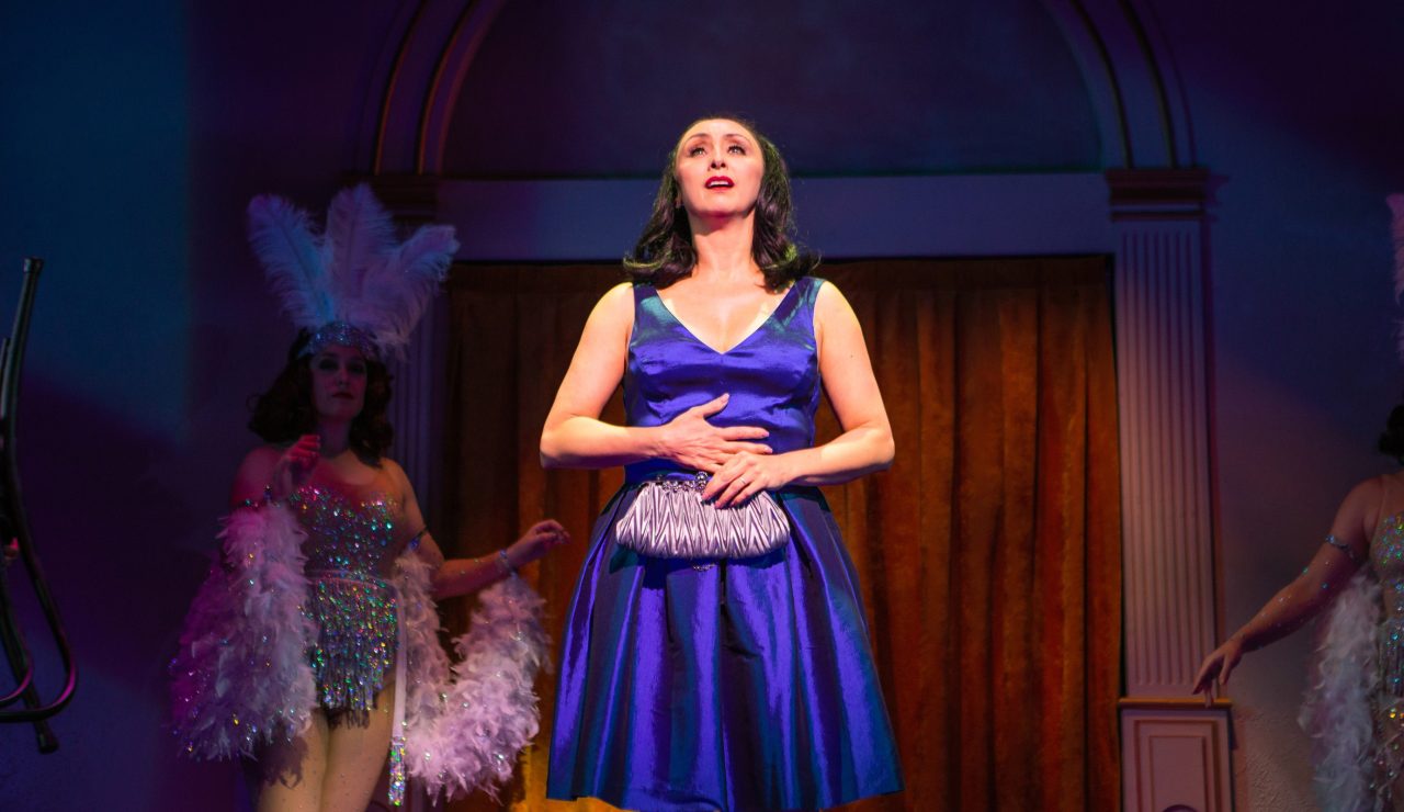 Former Follies performer Sally Durant Plummer (Natascia Diaz*) arrives at the theatre for the reunion, reminiscing about the Follies of the past (Danielle Cheiken, in the background).