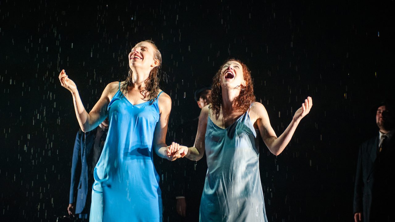 Manke, played by Halina (Rivka Borek*, left) and Rifkele, played by Chana (Malka Wallick*, right) embrace the rain in the legendary "rain scene" of Sholem Asch's 'The God of Vengeance', the play within the play, as Lemml (Dean Linnard*) and Mendel (Ted Zoldan) look on. Production photography by Jessica Palopoli for 'Indecent' by Paula Vogel at San Francisco Playhouse.