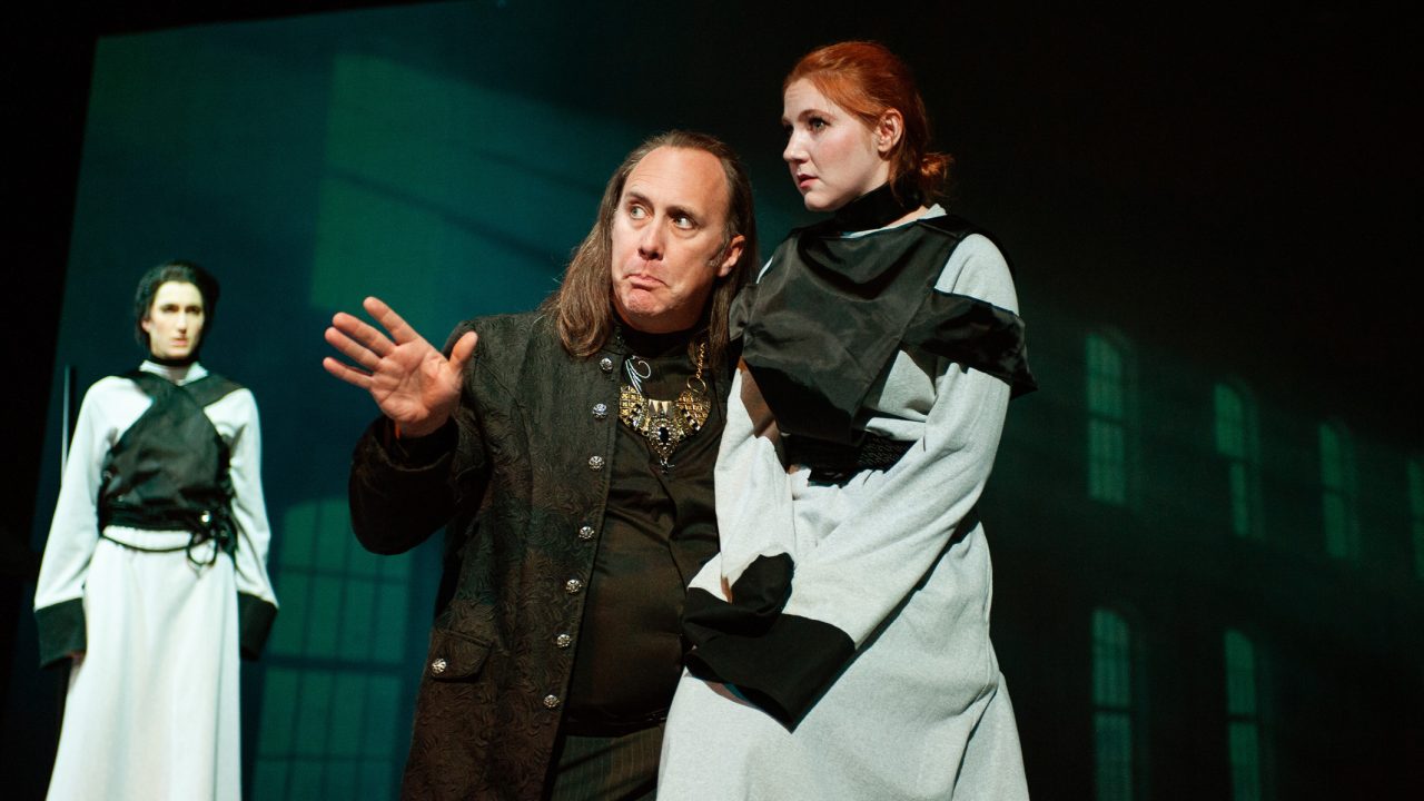 Rosalind (River Navaille) watches as her uncle Duke Frederick (Will Springhorn Jr.) speaks with his daughter Celia (Abigail Esfira Campbell) about banishing Rosalind from court in San Francisco Playhouse's musical version of "As You Like It," performing now through January 14, 2023.