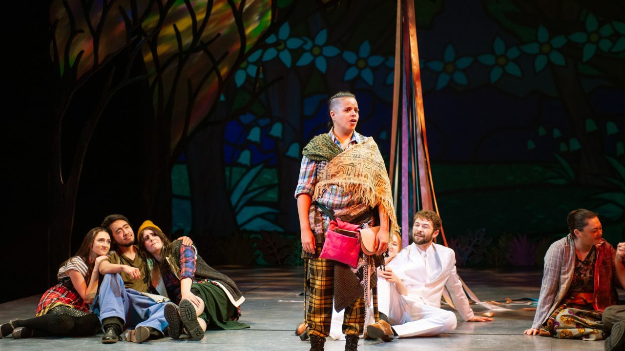 Jaques (center: Deanalís Arocho Resto) tells the Ardenites that "all the world's a stage" in San Francisco Playhouse's musical version of "As You Like It," performing now through January 14, 2023.