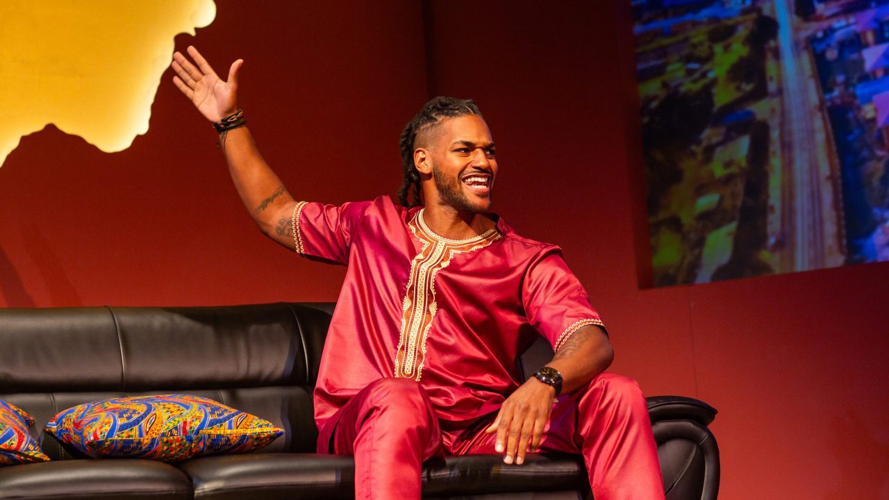 Nigerian film director Gbenga (Tre’Vonne Bell) dishes on a talk show in San Francisco Playhouse's "Nollywood Dreams," performing September 28 - November 4, 2023.