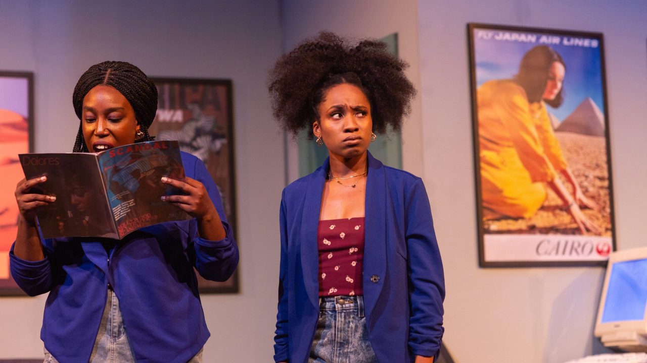 Dede (Brittany Nicole Sims) reads celebrity gossip to a skeptical Ayamma (Angel Adedokun) in San Francisco Playhouse's "Nollywood Dreams," performing September 28 - November 4, 2023.