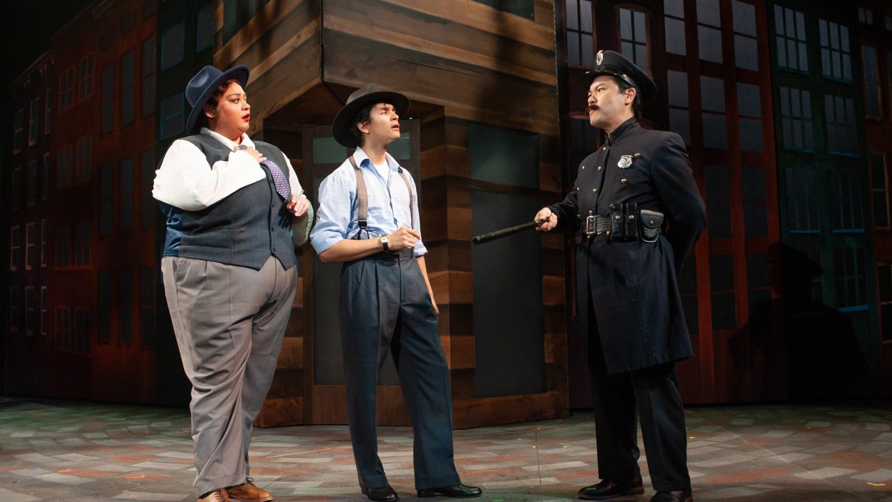 Nicely-Nicely (Kay Loren) and Benny (Chachi Delgado) are confronted by Lieutenant Brannigan (Alex Hsu) in San Francisco Playhouse's "Guys and Dolls," performing November 16, 2023 - January 13, 2024.