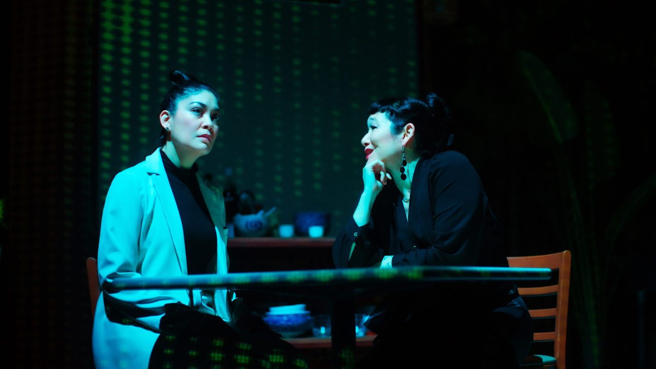 Vera (Rinabeth Apostol) is visited by CEO Gigi (Erin Mei-Ling Stuart) in San Francisco Playhouse's World Premiere Play "My Home on the Moon," performing January 25 - February 24.