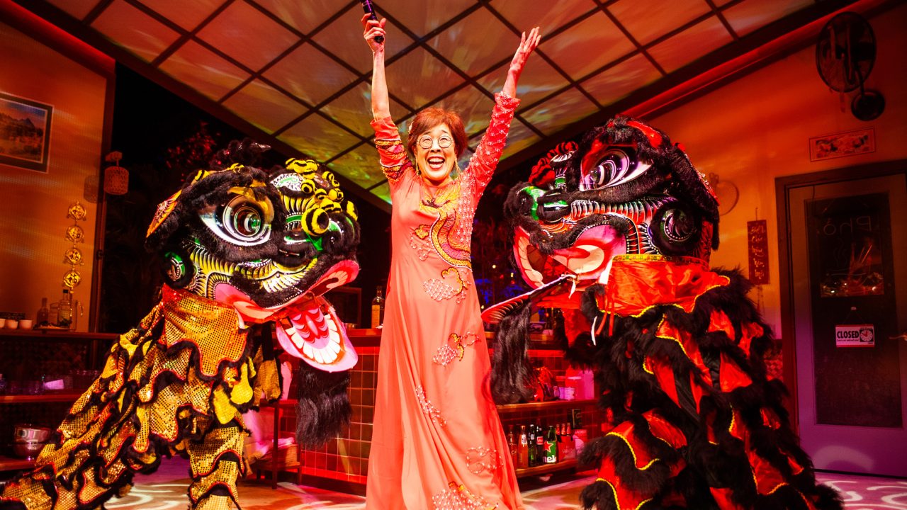 Lan (Sharon Omi - center) celebrates the new year with lion dancers (left - Erin Mei-Ling Stuart, right- Will Dao) in San Francisco Playhouse's World Premiere Play "My Home on the Moon," performing January 25 - February 24.