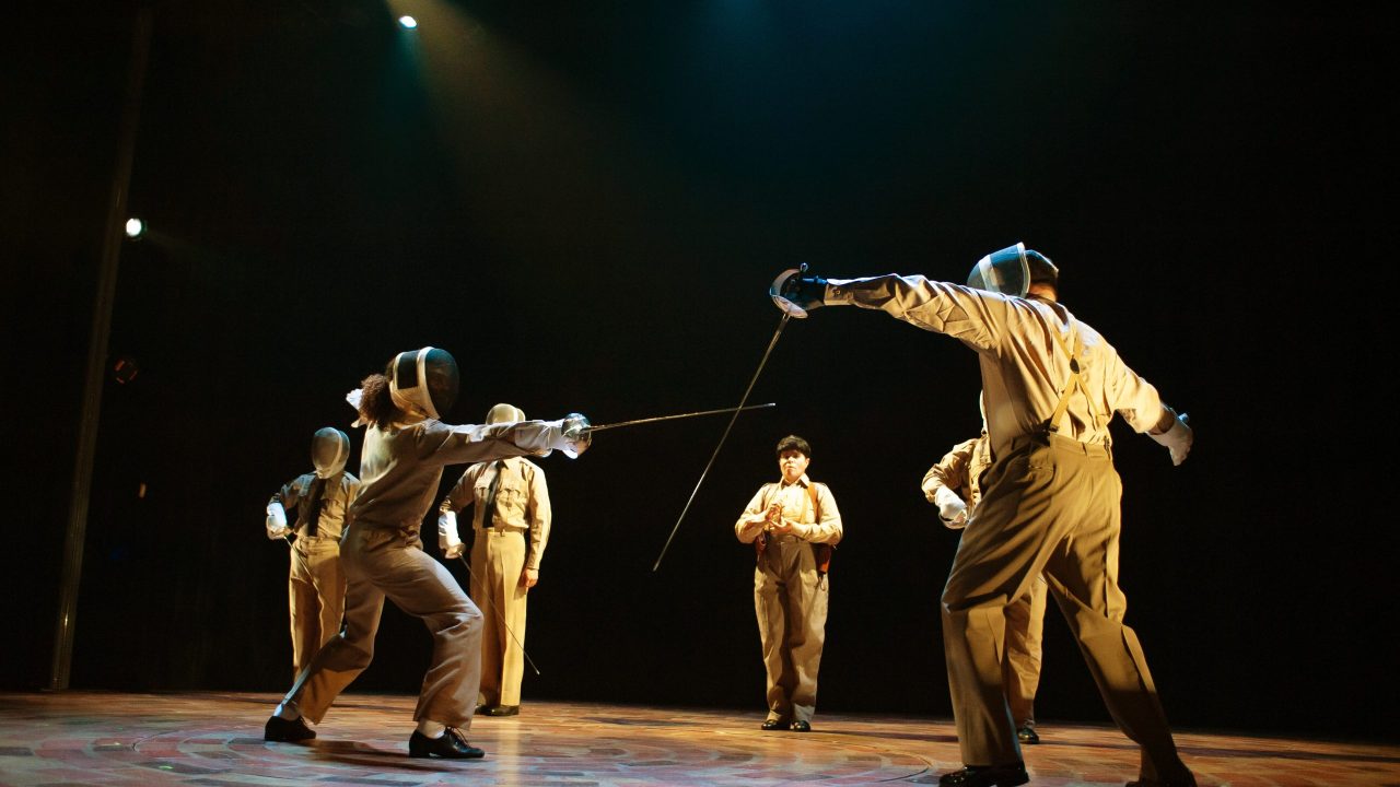 Juan Perón (right - Peter Gregus) and his fellow military comrades compete in fencing to display their power and strategy in San Francisco Playhouse's "Evita," performing June 27 - September 7, 2024. Juan Perón (right - Peter Gregus) and his fellow military comrades compete in fencing to display their power and strategy in San Francisco Playhouse's "Evita," performing June 27 - September 7, 2024.