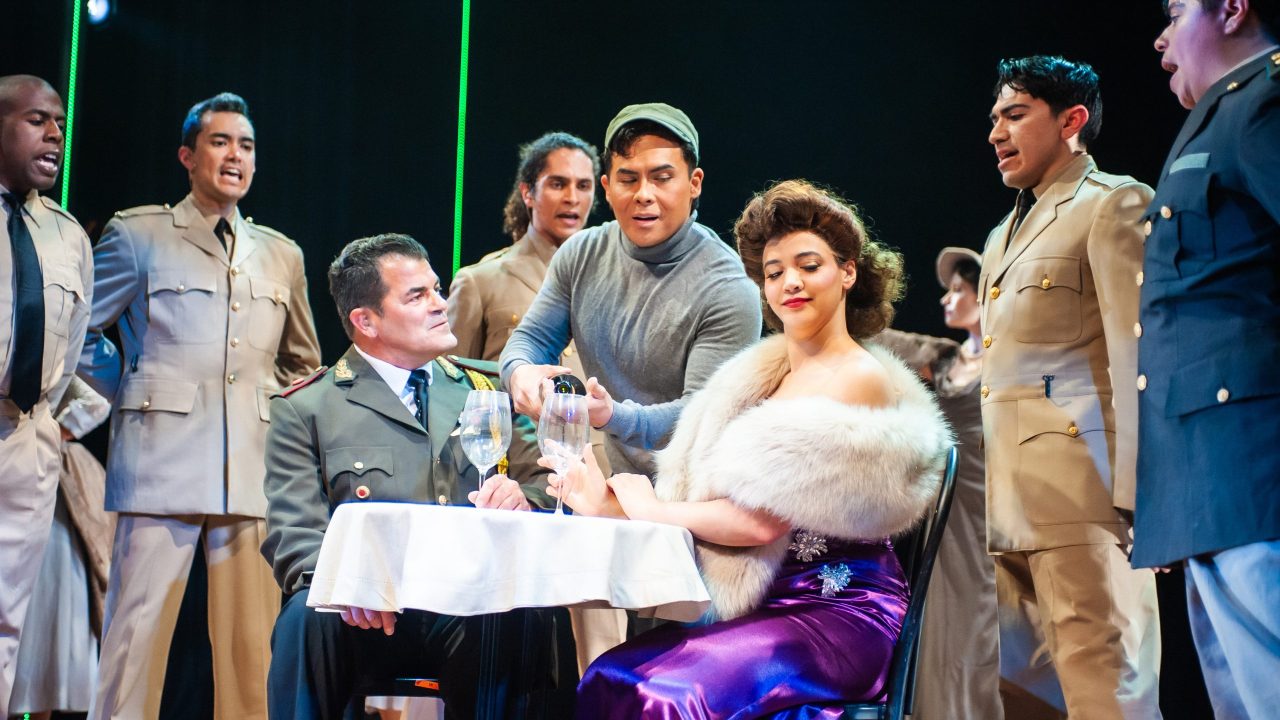 Juan Perón (Peter Gregus) is charmed by radio star Eva Duarte (Sophia Alawi) as Che (left - Alex Rodriguez) and the crowd look on in San Francisco Playhouse's "Evita," performing June 27 - September 7, 2024. Juan Perón (Peter Gregus) is charmed by radio star Eva Duarte (Sophia Alawi) as Che (left - Alex Rodriguez) and the crowd look on in San Francisco Playhouse's "Evita," performing June 27 - September 7, 2024.