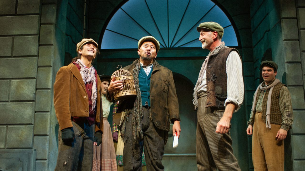 Jamie (Chachi Delgado) listens to Alfred's (Jomar Tagatac) latest scheme which fascinates Harry (Andy Collins) and other cockney folks (Julio Chavez) in San Francisco Playhouse's "My Fair Lady," performing July 3 - September 13, 2025. Jamie (Chachi Delgado) listens to Alfred's (Jomar Tagatac) latest scheme which fascinates Harry (Andy Collins) and other cockney folks (Julio Chavez) in San Francisco Playhouse's "My Fair Lady," performing July 3 - September 13, 2025.