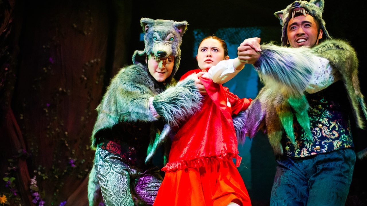 Little Red Riding Hood (Olivia Hellman) is ambushed by two wolves (left - Trevor March, right - Johann Santiago Santos) in San Francisco Playhouse's "Into the Woods," performing November 20, 2025 - January 17, 2026. Little Red Riding Hood (Olivia Hellman) is ambushed by two wolves (left - Trevor March, right - Johann Santiago Santos) in San Francisco Playhouse's "Into the Woods," performing November 20, 2025 - January 17, 2026.